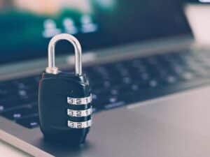 Cybersecurity represented by a physical lock sitting on a laptop